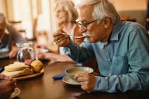 stockphotomaturemaneatingsoupwhilehavinglunchatresidentialcarehome2189378985.jpg