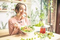 stockphotoyoungwomaneatinghealthyfoodsittinginthebeautifulinteriorwithgreenflowersonthe1028139955.jpg