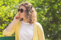 Žena zamišljena sedi u parku ima naočare za sunce