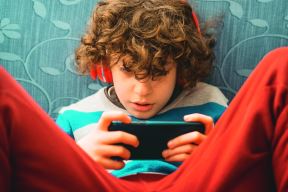 stockphotoschoolagedkidlisteningasmartphonethrutheheadsetrelaxingonthecoachindoorchildren1717609405.jpg