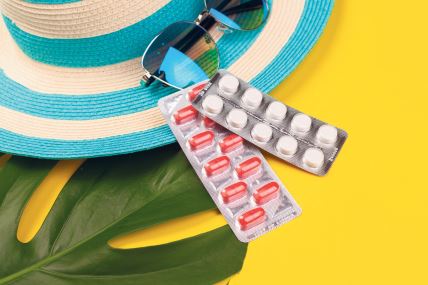 stockphototopviewonwhiteandredpillsinblisterpackbluehatsunglassesmonsteraleafonyellow2103246335.jpg