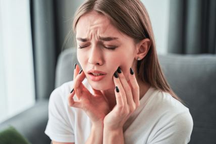 umnjaci-glavna--stockphototoothachegirlsufferingfromtoothpainandtouchingcheekwhilesittingoncouchathomedental1845308947.jpg