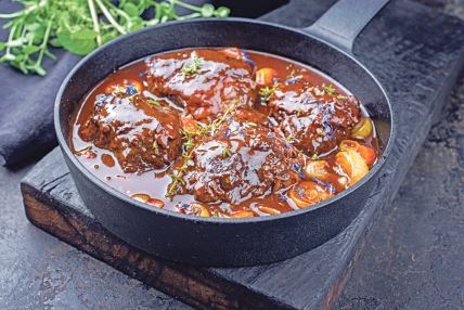stockphototraditionalgermanbraisedbeefcheeksinbrownredwinesaucewithcarrotsandonionsofferedas1573994452.jpg
