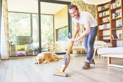 stockphotosmilinghousemanattheparquetfloorvacuumingthelivingroom1519208924.jpg