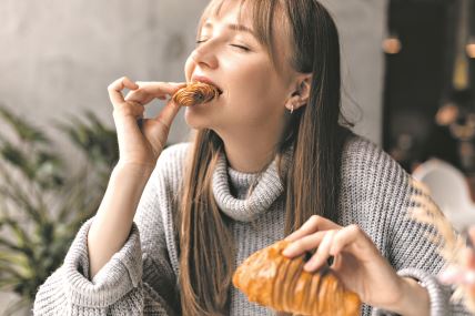 stockphotoyoungblondewomanwithbangeatingcroissantsatacafegirlbitepieceofcroissantlookjoyful2299982201.jpg