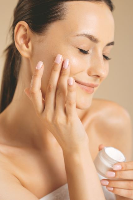 stock-photo-sensual-young-woman-with-bare-shoulders-applying-cream-on-face-in-studio-caucasian-female-model-2130747482.jpg