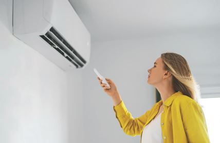 stock-photo-woman-holding-remote-control-aimed-at-the-air-conditioner-2120547839.jpg