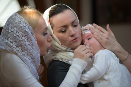 Krštenje male devojčice majka je drži