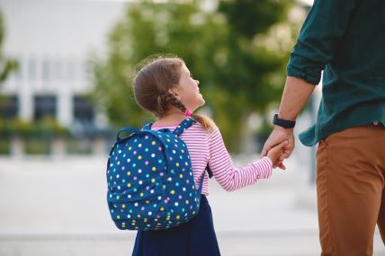 Devojčica sa rancem na leđima kreće u školu sa tatom