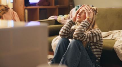 Umorna devojka sedi na podu dnevne sobe