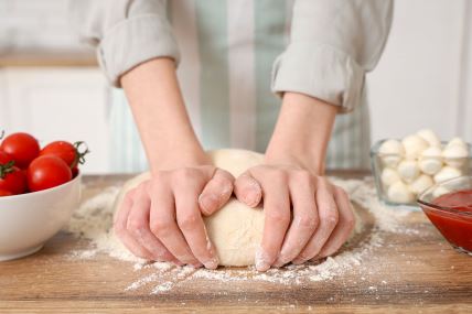 stock-photo-woman-kneading-dough-for-pizza-near-table-in-kitchen-2562956219.jpg