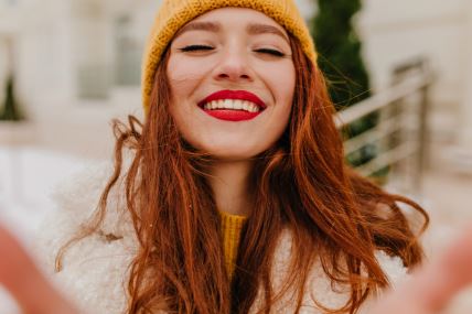 Devojka sa žutom kapom na glavi osmehuje se