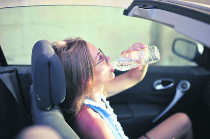 stock-photo-blonde-woman-drinking-water-in-the-car-1183521037.jpg