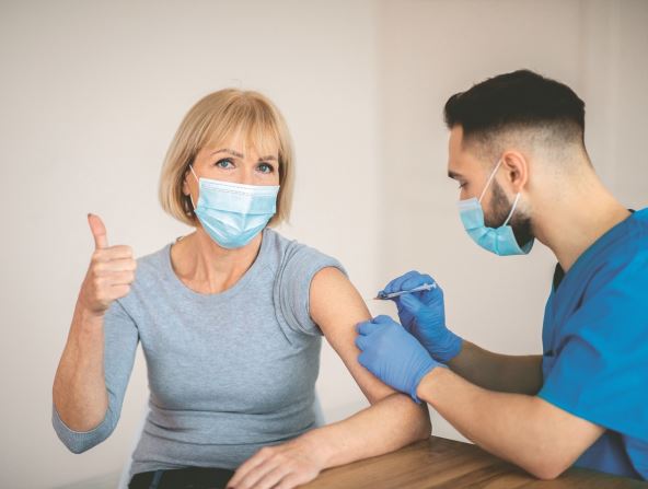 znacaj-vakcine---stockphotomaturewomaninfacemaskapprovingofcovidvaccinationshowingthumbupgestureduring1891539526.jpg