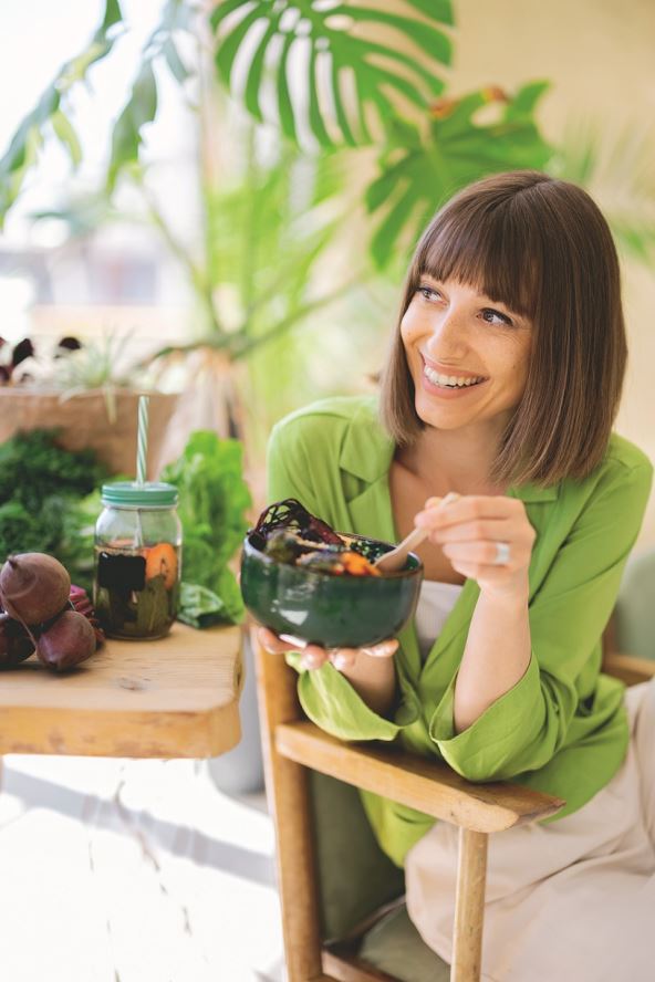 zdrava-ishrana-stockphotoyoungcheerfulwomaneatsvegetarianlunchinbowlsittingbythetablefulloffreshfood2180168315.jpg