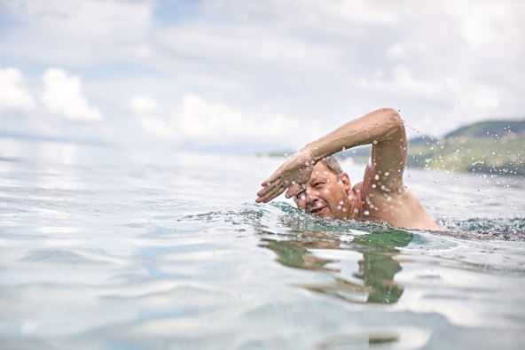 stockphotoseniormanswimmingintheseaoceanenjoyingactiveretirementhavingfuntakingcareof209479369.jpg