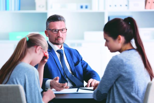 stockphotoyoungwomanwithdaughterduringteacherparentmeetingatschool590602514.jpg