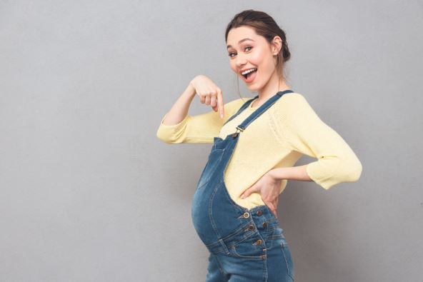 stockphotopictureofhappypregnantwomanposingisolatedovergreywalllookingatcameraandpointing608893907.jpg