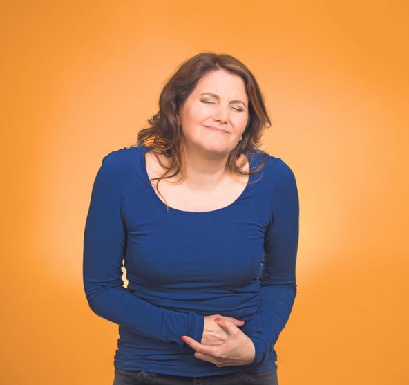 stockphotoyoungstressedwomanhavingstomachpainhandsonbellyhavingbadachespainsisolatedorange213980959.jpg