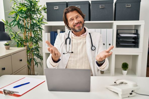 doktor---stockphotohandsomemiddleagedoctormanworkingattheclinicsmilingcheerfulofferinghandsgiving2176217891.jpg