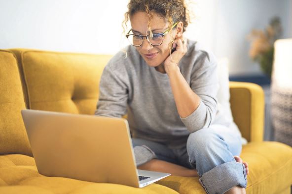 stockphotofemalesittingonayellowcouchusinglaptopandinternetconnectionandsmilehappywomanin2184941147.jpg