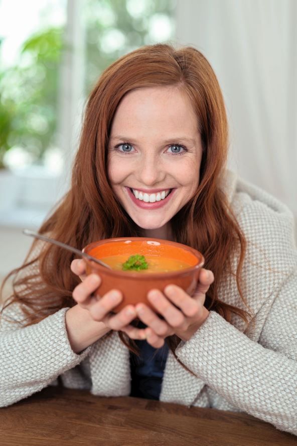 glavna--stockphotocloseuphappywomaninwinteroutfitholdingabowlofhotsoupandsmilingatthecamera313694426.jpg