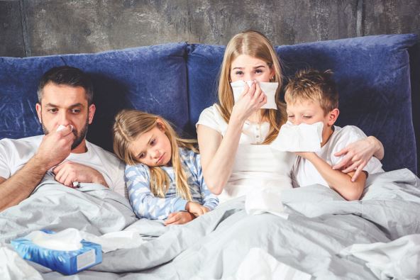 stockphotofamilyoffourhasaflueandlyingonbedtogether570823792.jpg