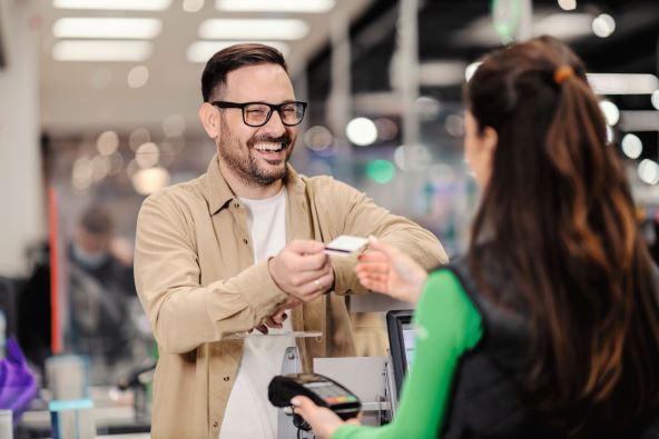 sta-je-ljubaznost---stockphotoasmilingmangivingcreditcardtoacashierandpayingforgroceriesinsupermarket2127946706.jpg