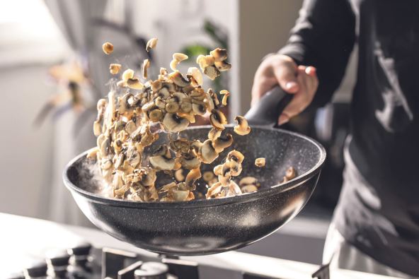 pecurke--stockphotocloseupofprofessionalchefcookhandsroastschampignonswithcreaminwokpanformediterranean2201726205.jpg