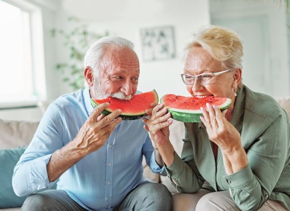 stockphotoportraitofahappyseniorcoupleembracingeatingwatermelonandhavingfunathome2362481341.jpg