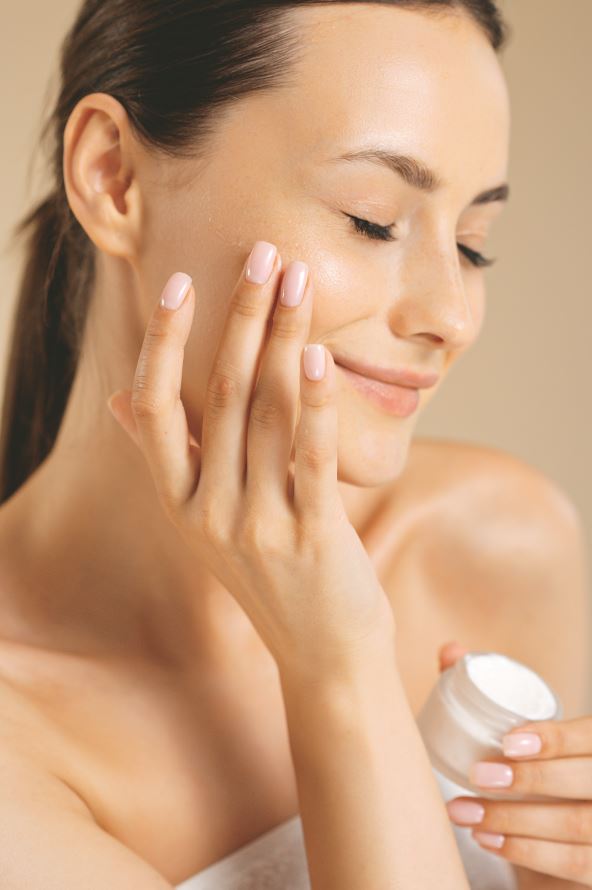 stock-photo-sensual-young-woman-with-bare-shoulders-applying-cream-on-face-in-studio-caucasian-female-model-2130747482.jpg