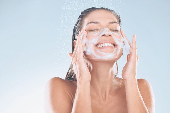 stock-photo-woman-facial-and-soap-for-skincare-hygiene-with-foam-wash-or-clean-against-blue-studio-background-2472679875.jpg