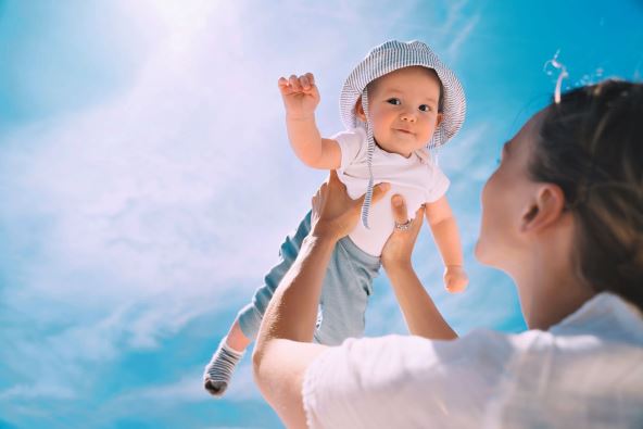 stock-photo-mother-throwing-baby-up-against-the-blue-sky-happy-family-outdoors-mom-and-baby-at-summer-on-2145071331.jpg