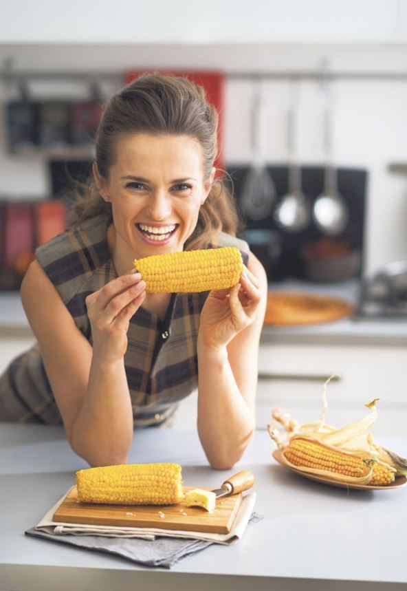 stock-photo-portrait-of-happy-young-housewife-eating-boiled-corn-in-kitchen-251028433.jpg