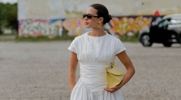 Moderna devojka u beloj haljni sa zlatnim nakitom uživa u gradu