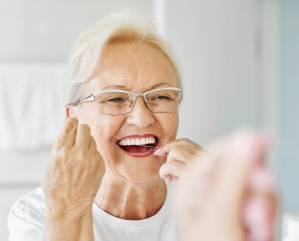 Starija žena koristi konac za zube