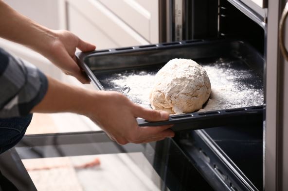 stock-photo-young-man-putting-raw-bread-into-oven-in-kitchen-1325581280.jpg