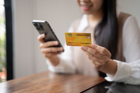 Devojka koristi kreditnu karticu za plaćanje na telefonu