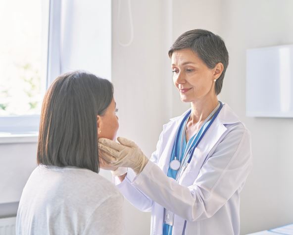 stock-photo-friendly-middle-aged-woman-doctor-wearing-gloves-checking-sore-throat-or-thyroid-glands-touching-2026641008.jpg