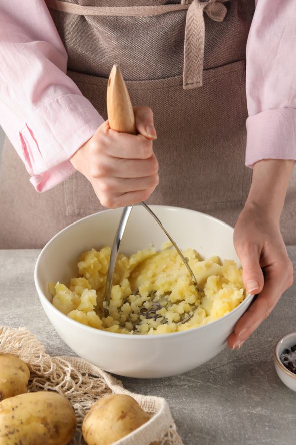 stock-photo-woman-making-mashed-potato-at-light-grey-table-closeup-2258568047.jpg