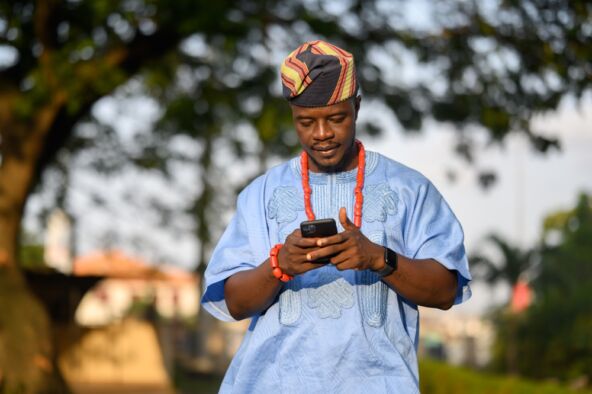 Čovek u tradicionalnoj nošnji gleda telefon.jpg