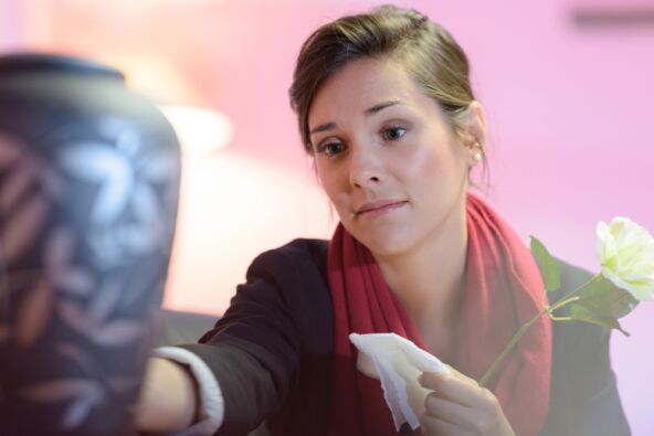 Ožalošćena žena gleda u urnu sa pepelom