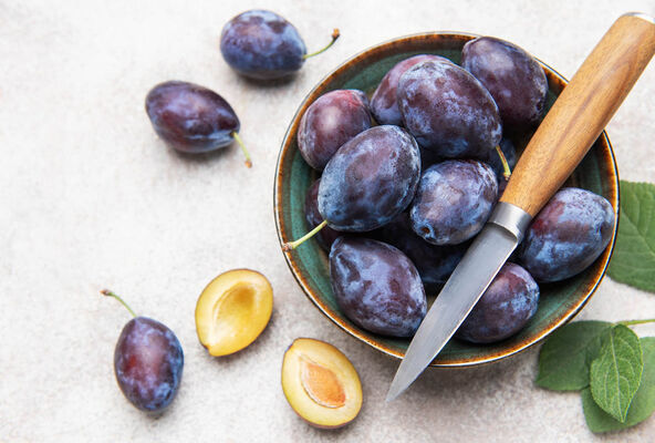 stock-photo-ripe-purple-plums-in-a-green-bowl-with-a-knife-featuring-cut-plums-on-a-light-background-2687190157.jpg