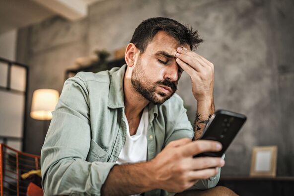 stock-photo-portrait-of-adult-furious-man-sit-on-chair-and-text-sms-on-cellphone-2497934935.jpg
