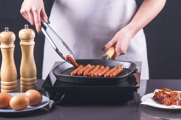 POVREMENO IH OKRENITE   stock-photo-young-woman-in-a-gray-apron-fries-sausages-1398418514.jpg