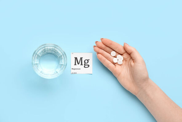 stock-photo-female-hand-with-magnesium-pills-and-glass-of-water-on-blue-background-2231607179.jpg