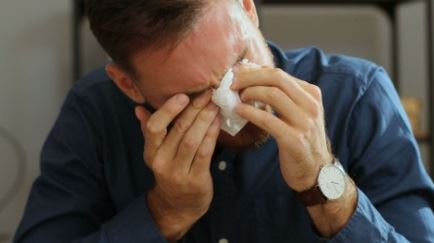 Muškarac koji plače i drži maramicu